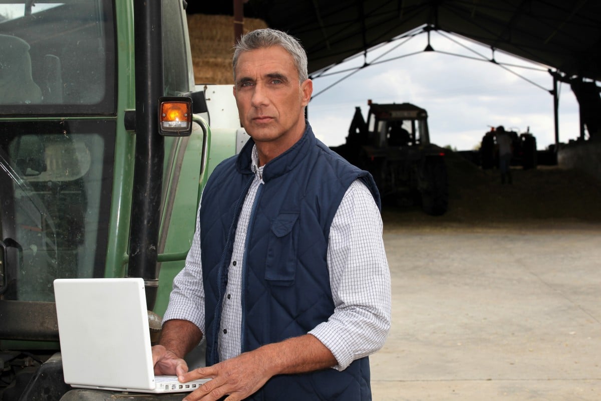 farmer-with-laptop-stood-by-tractor